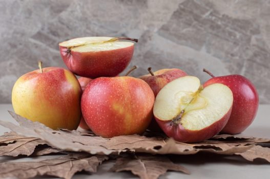 Plane tree leaves under a bundle of sliced and whole apples on marble background Plane tree leaves under a bundle of sliced and whole apples on marble background. High quality photo